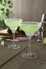 Delicious Margarita cocktail in glasses on wooden table, closeup