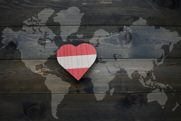 wooden heart with national flag of austria near world map on the wooden background.