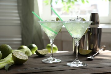 Delicious Margarita cocktail in glasses and lime on wooden table