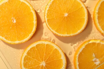 Slices of juicy orange and water on beige background, flat lay