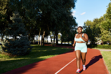 An African American woman in sportswear runs with determination on a vibrant red track, embodying...