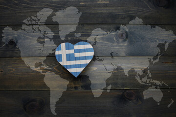 wooden heart with national flag of greece near world map on the wooden background.