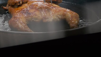 the chef flips a whole grilled chicken with a large fork