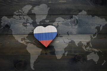wooden heart with national flag of russia near world map on the wooden background.
