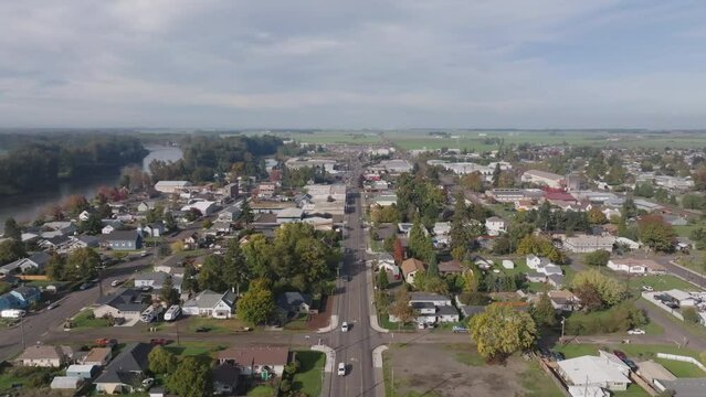 Aerial drone shot of small neighborhood town in Oregon with green hills, mountains, and clouds.