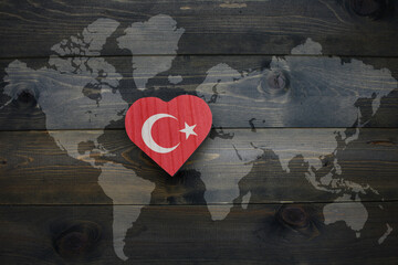 wooden heart with national flag of turkey near world map on the wooden background.