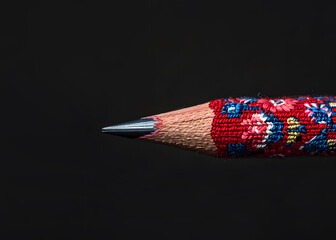 A pencil against dark background, traditional folklore knitted pattern