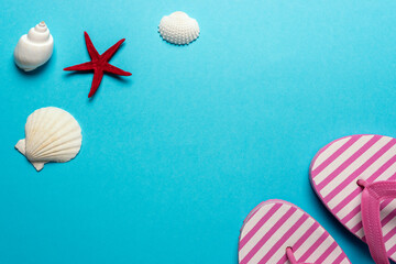 Creative composition with seashells and beach slippers on blue background. Summer minimal concept.