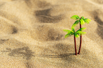 Fototapeta na wymiar Tropical palm toy on sand background. Creative minimal summer concept.