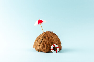 Tropical beach concept made of coconut fruit and sun umbrella. Creative minimal summer background.