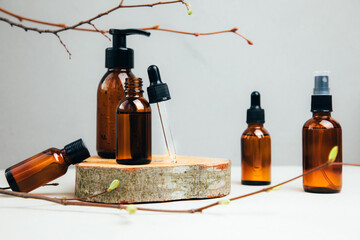 Set of natural cosmetics. Amber bottles with facial, bath liquid on a concrete background with...