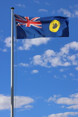 Western Australia flag flying in wind.  Blue sky, some clouds. Copy space.