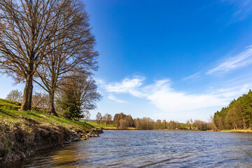 Spring lake view with blue sky. - obrazy, fototapety, plakaty