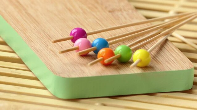 man puts wooden sticks with multicolored round for pinchos tips on the board
