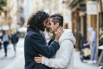 Affectionate male couple in love standing close to each other outdoors.