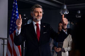 Positive United States Presidential Candidate gestures and poses for cameras after inspirational campaign speech or interview for media and television news. American politician at press conference.