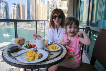 Mother and doughter having breakfast breakfast with a view of Dubai marina.