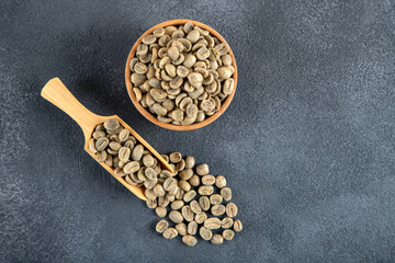 A wooden spoon filled with green coffee beans, top view