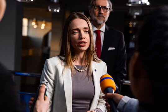 Political speech of EU consul during press campaign. Confident female European politician answers journalists questions, gives interview for media and television news in European Parliament building.