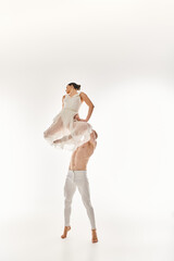 A shirtless young man and a woman in a white dress dance together, performing acrobatic elements in...