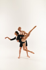 Fototapeta na wymiar Shirtless young man and woman dance in mid-air, executing acrobatic moves in a studio setting against a white backdrop.
