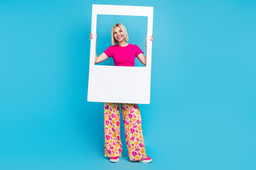 Full body photo of attractive young woman hold instant photo frame dressed stylish pink clothes isolated on blue color background