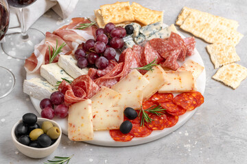 Charcuterie plate with Italian salami and prosciutto ham, with gorgonzola cheese and pecorino cheese with herbs, served with olives and grapes. appetizer platter for aperitif
