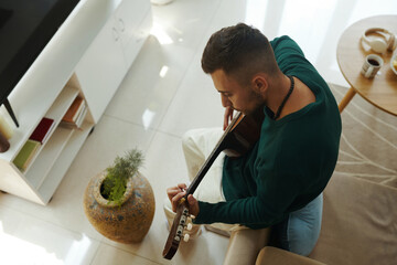 Creative young man learning playing guitar at home, view from above - 782091463