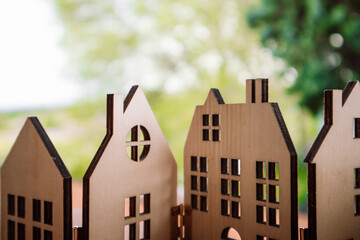 Wooden toy houses against natural green blurred background. A home in a forest, wood. Cardboard house window, roofs. Ecological rural buildings.