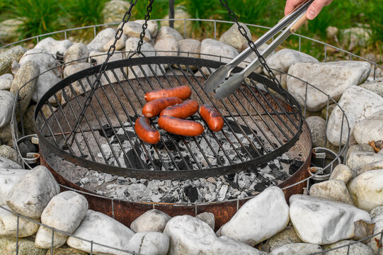 Grill w ogrodzie, gorąca kiełbasa przekręcana na ruszcie na drugą stronę 