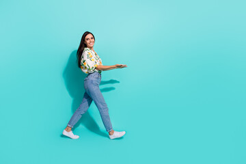 Fototapeta na wymiar Photo of lovely girl wear trendy clothes going store center demonstrating special seasonal sale blank space isolated on cyan color background