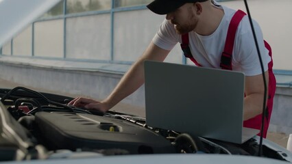 At automotive service center mechanic skillfully attends to car with hood exposed, embodying role of repair master and demonstrating importance of their work in ensuring reliable car repair services.