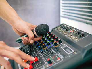 Hand Sound engineer  holding microphone on sound mixer in live broadcasting studio producer for...