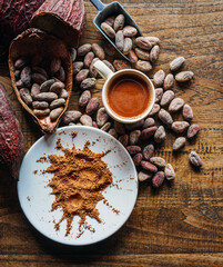 Top view of hot chocolate drink,cocoa drink and natural cocoa powder with brown cocoa beans and dry cacao pod  on a vintage wooden table. - obrazy, fototapety, plakaty