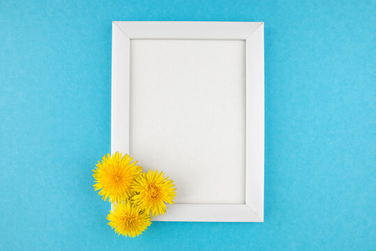 White wooden photo frame and flowers on blue background