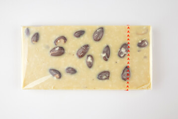 bar of white chocolate with nuts on white. Chocolate in transparent packaging on a white background.