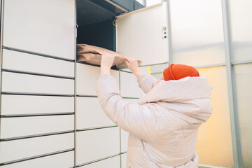 Woman putting box to automated parcel machine.