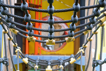 Close-up view of colorful playground rope bridge for children's outdoor recreational equipment in a...
