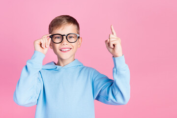 Photo of small clever boy arm touch eyewear point finger up empty space isolated on pink color...