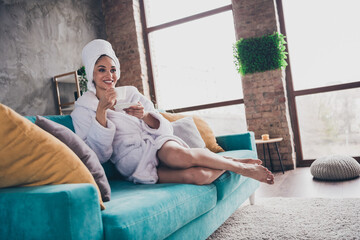 Photo portrait of attractive young woman sit sofa drink tea head wrapped towel dressed bath robe home interior enjoy weekend - obrazy, fototapety, plakaty