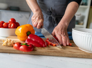 Woman chopping red bell peppers on a cutting board in the kitchen