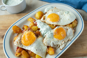 Fried potatoes with fried eggs sunny side up and herb sauce