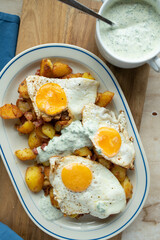 Fried potatoes with fried eggs sunny side up and herb sauce