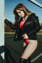 Sexy girl at the stadium in a bodysuit and leather jacket © komokvm