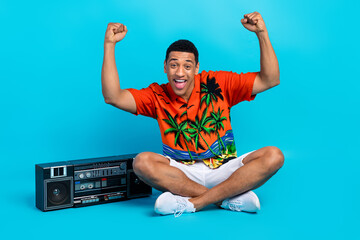 Full size portrait of nice young man boombox music raise fists summer holiday isolated on blue color background