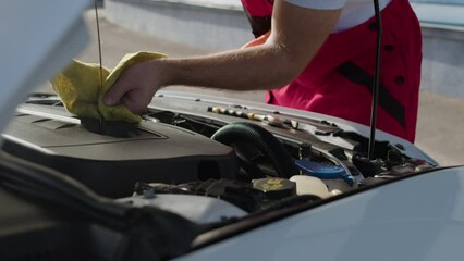 At auto repair shop mechanic carefully examines oil levels in car engine, underscoring significance of regular oil checks in preventing potential engine issues and ensuring smooth operation on road.