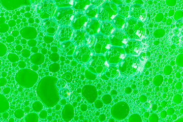 abstact background foam bubbles on detergent and fat water emulsion in green tones close up