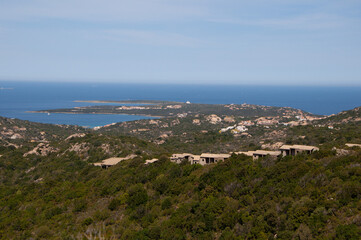 Fototapeta na wymiar Serene landscape with a green shoreline and blue waters. Capo Ferro, Sardinia, Italy