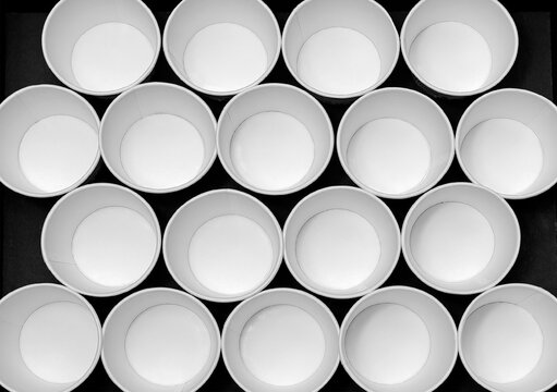Modern minimal art creativity, Abstract  food product background. Many Empty white paper cups arranging pattern on 
black background.