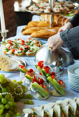 catering buffet table food, canape, slices of vegetables, cucumbers, sausage, grapes, fruits,...